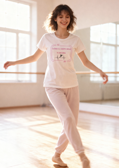 Joven sonriente en pijama, bailando en un estudio iluminado por la luz natural.